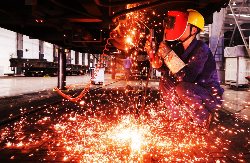 倪高明對貨車底部制動閥安裝罩裂紋進行電焊修補。汪晟攝