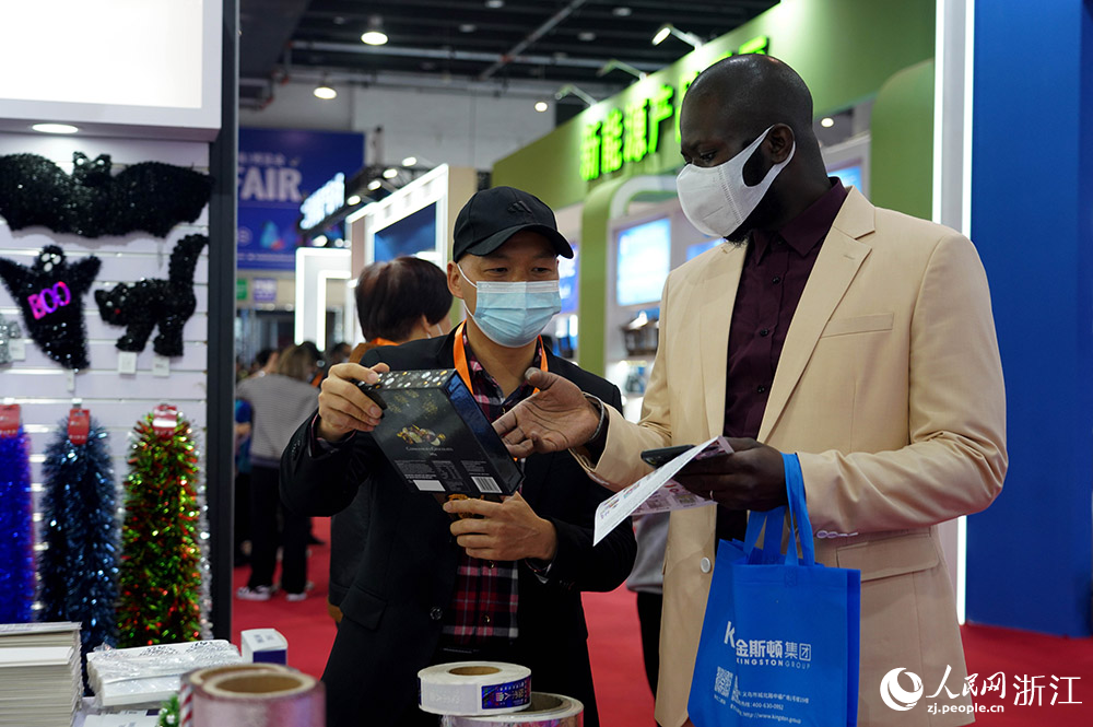 11月24日，來自塞內加爾的客商吉他（右一）在義烏國際博覽中心了解商品。人民網 章勇濤攝