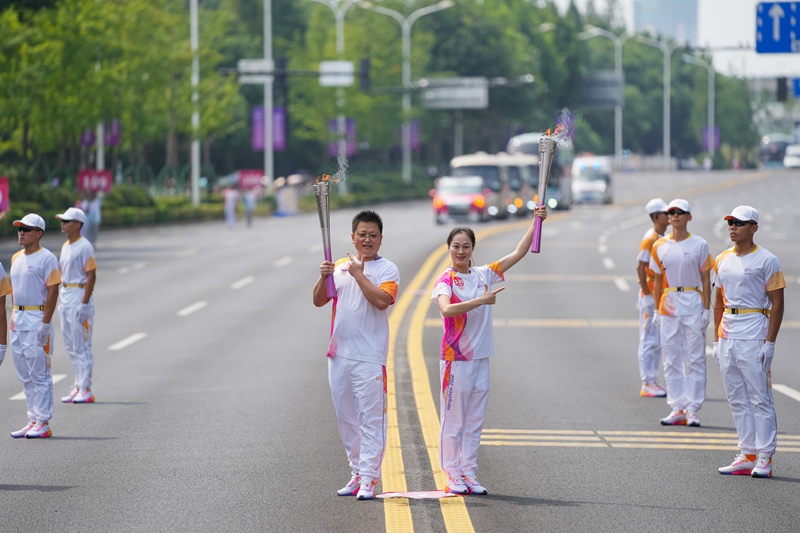 苗春雨（左）在亞運會火炬傳遞活動紹興站傳遞火炬。受訪者供圖