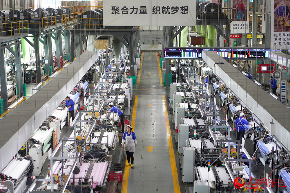 浙江省紹興市新昌縣達利絲綢智能工廠內一派繁忙，工人在生產線上趕制訂單。人民網 章勇濤攝