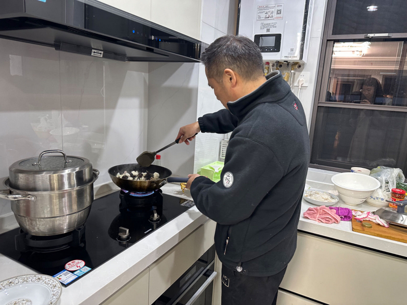 陳阿根的兒子正在炒菜，慶祝遷入新居。李彩恩攝