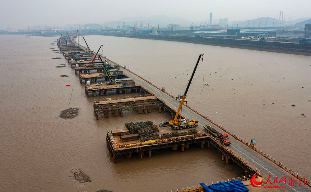 3月12日，在寧波市鎮海區灰鱉洋南岸灘涂之上，工人在棧橋搭建起的海上施工通道上有序施工。人民網 章勇濤攝