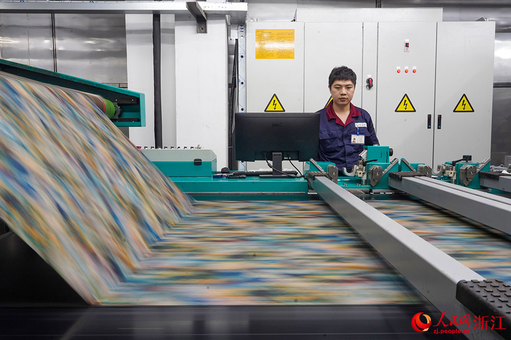 在浙江省紹興市柯橋區的印染企業，工人在數碼印花產線上趕制訂單。人民網 章勇濤攝