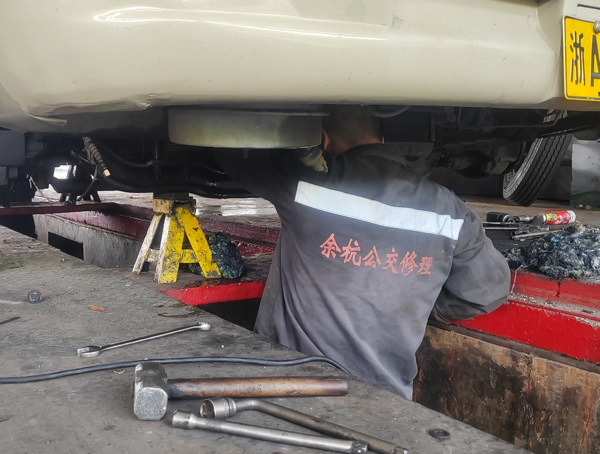 公交車維修工正在檢查車子底部情況。胡靜攝