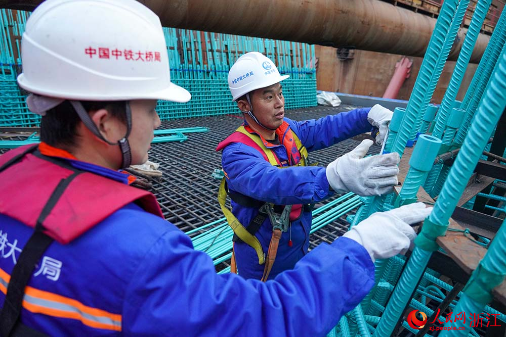 周朋（右）對9號墩塔座鋼筋安裝情況進行檢查。人民網 章勇濤攝