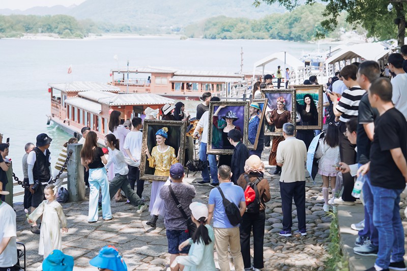 外國友人頭戴“移動畫框”，化身“行走的世界名畫”，穿梭在古堰畫鄉的街巷中，成為游客關注焦點。