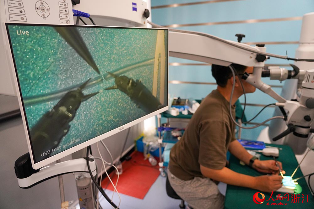 5月27日，研發人員使用顯微外科手術機器人進行仿真血管的吻合操作。人民網 章勇濤攝