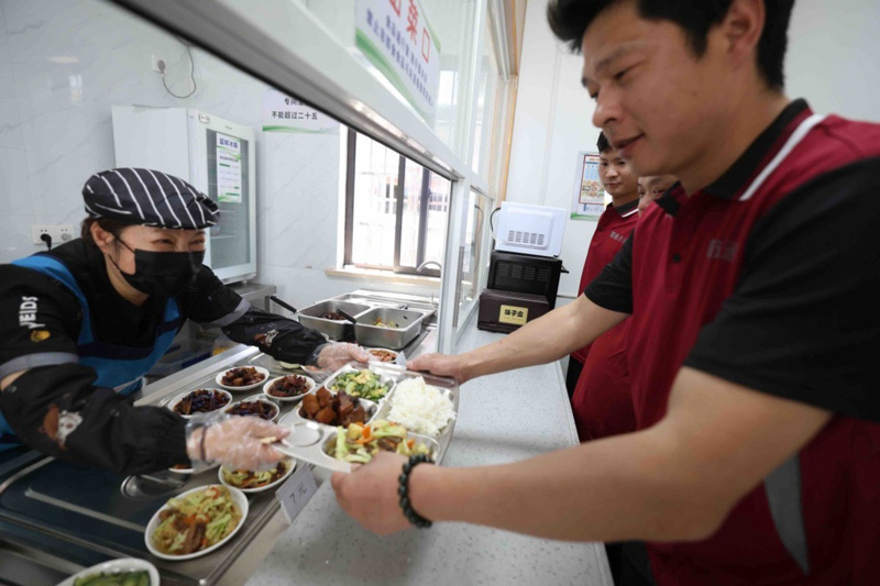 快遞員在食堂內打餐。甬江街道供圖