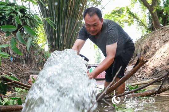 江勝華站在溝渠里調整水泵出水口。人民網 張俊攝